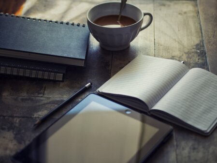 Stilvolle Papierstruktur mit Bleistift, Terminkalender und ipad und einer Tasse Kaffee als Symbol für Kontakt