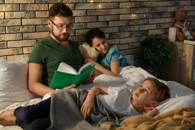Eltern lesen einem Kind abends eine Geschichte vor